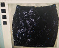 Black sequined fabric on a flat surface with a neutral background