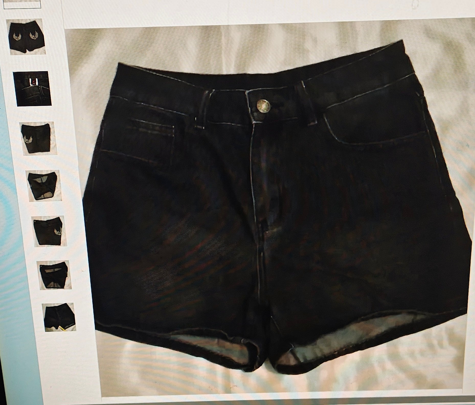 Black denim shorts on a light gray surface with a white frame.