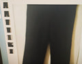 Black pants hanging on a rack with a white background