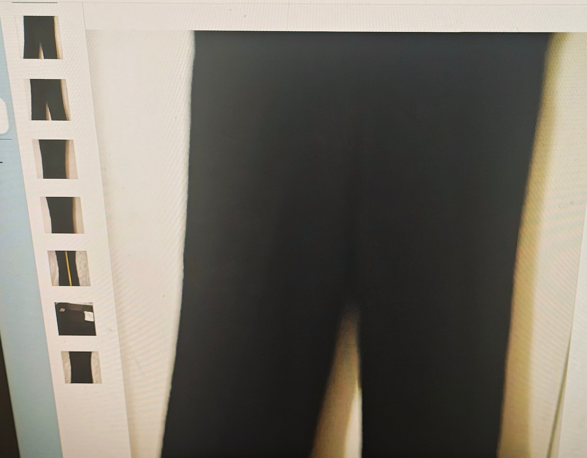 Black pants hanging on a rack with a white background