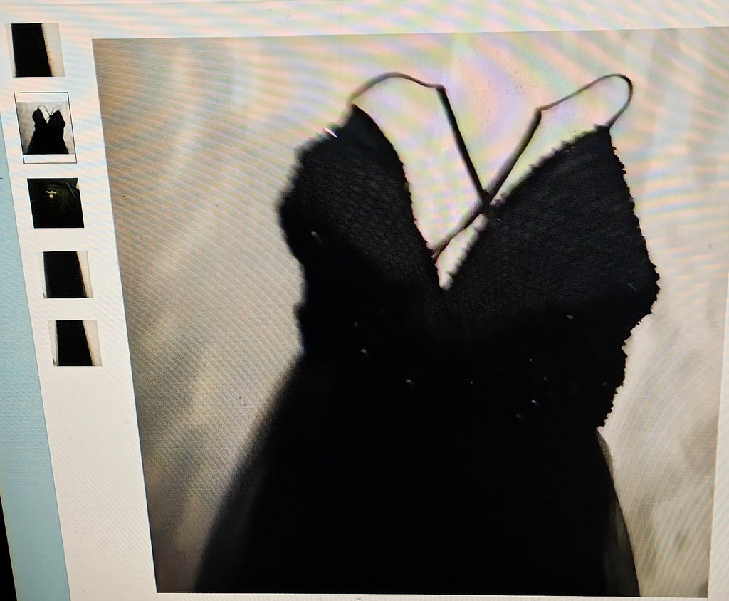 Black dress with thin straps on a textured beige background