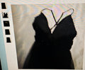 Black dress with thin straps on a textured beige background